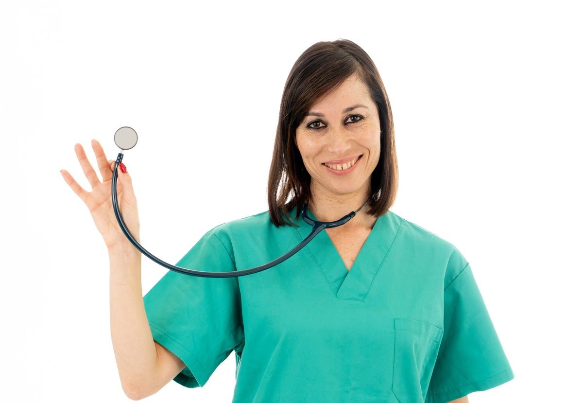 Young beautiful smiling medical professional female doctor or nurse holding stethoscope in green scrubs against white background with copy space in Health medical care and advertisement concept.