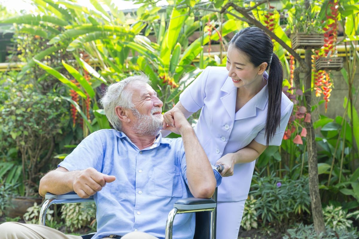 A nurse take care a senior male on wheelchair in his garden at home